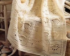 a white crocheted blanket sitting on top of a chair next to a basket