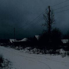 a snowboarder is going down a snowy road in the dark with power lines above