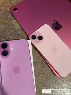 two pink iphones sitting next to each other on top of a stone countertop