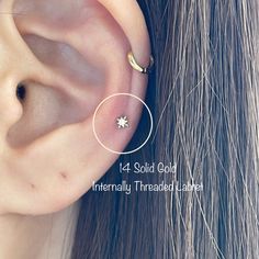 an ear piercing is shown with two small stars on the top and one smaller star in the middle