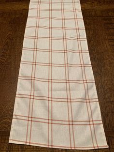 a white and orange plaid table runner on a wooden floor with wood floors in the background