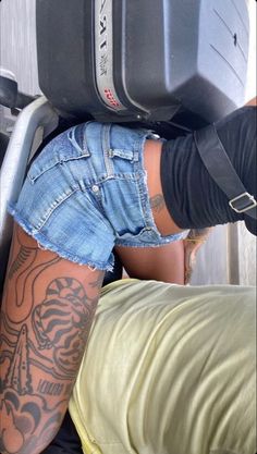 a person with tattoos on their legs is leaning against a wall and holding a suitcase