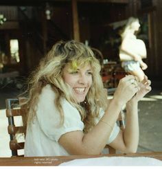 a woman sitting at a table with a knife and fork in her hand, smiling