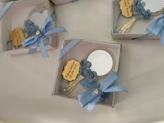 three small boxes with blue ribbons and tags on the sides, each holding a mirror