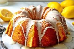 a lemon bunt cake with icing on a plate next to some lemons