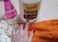 a woman is pointing at something on the floor next to her hand and an orange shirt