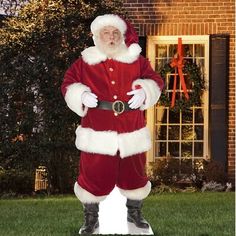 a man dressed as santa claus standing in front of a house with his hands on his hips