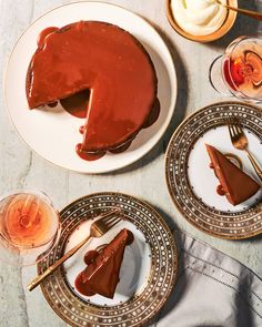 a table topped with plates and desserts covered in chocolate cake next to wine glasses