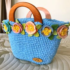 a crocheted blue purse with flowers on it