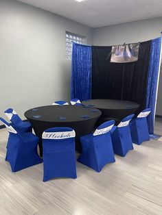 a conference room set up with blue chairs and black table cloths for an event