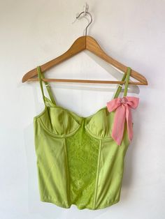 Vintage Victoria’s Secret Lime Green Bustier. A cutesy femme bustier with lace panel going down the front of the bodice and along the tops of the cups. Has boning and underwire. Delicate flower pattern stitched into the silk. Pink bow with circular rhinestone buckle adorning the left strap. In excellent condition. Body is a poly blend, bow is 100% silk. Hand wash cold. Marked size 36B. Approximate Measurements: Cup width: 6" Cup height without lace: 4" Underarm to underarm: 16" Length: 18" Ryan Roche, Christian Wijnants, Ace And Jig, Raquel Allegra, Black Crane, Rachel Comey, Lace Panelled, Green Silk, Delicate Flower