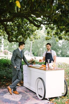 two men in suits are standing at a food cart