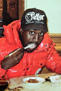 a man sitting at a table with food in front of him and wearing a hat