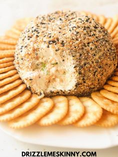 a cheese ball on top of crackers is sitting on a white plate with black sprinkles