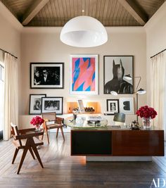 a living room filled with furniture and pictures hanging on the wall above a wooden table