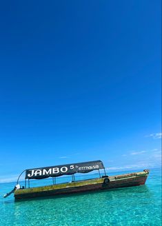 a boat that is floating in the water near some sand and blue sky with no clouds