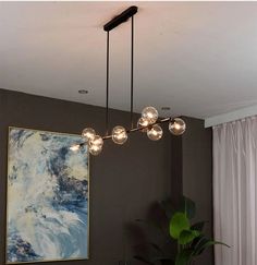 a modern chandelier hanging from the ceiling in a living room with paintings on the wall