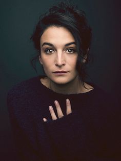 a woman is posing for a photo with her hand on her chest and looking at the camera