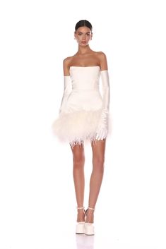 Elevate your elegance with the Fiora White Bridal Mini Dress from our La Danse Blanche collection. Strapless, square neckline Boned bodice Feather-trimmed hem Corset and back zipper closure Gloves not included White Feather Mini Dress, Sleeveless Wedding Dress With Gloves, Reception Dress Feathers, After Party Bridal Dress, Winter Wedding Reception Dress, Feather White Dress, Vintage Short Wedding Dress, Tutu Wedding Dress, Mini Bridal Dress