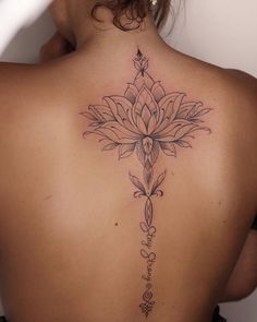 the back of a woman's neck with a flower tattoo on it