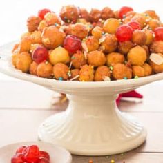 a white cake plate filled with fruit covered in sprinkles and candies