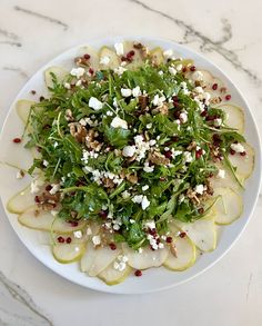 a white plate topped with sliced pears and feta cheese on top of it