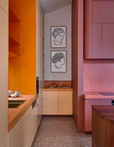 an orange and pink kitchen with two pictures on the wall