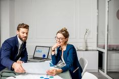 two people sitting at a table with papers