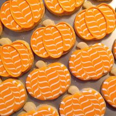 many decorated cookies are arranged in rows on a tray with white and orange icing