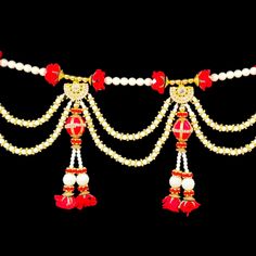 a red and white beaded necklace with bells, beads and flowers on black background