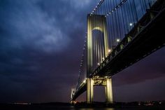 the bridge is lit up at night with lights shining on it's sides and below