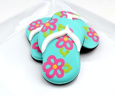 decorated cookies in the shape of flip flops on a white platter with pink and blue flowers