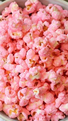 a bowl filled with pink popcorn sitting on top of a table