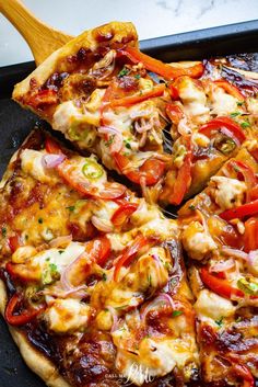 a pizza sitting on top of a pan covered in cheese and toppings next to a wooden spatula