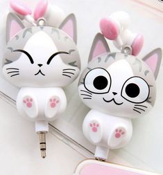 two white cats with black eyes are plugged in to a pink phone charger