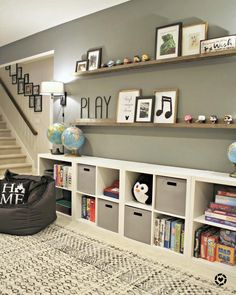 a living room filled with lots of furniture and bookshelves next to a stair case