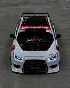 the front end of a white car with red lettering on it