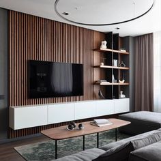 a living room with a couch, coffee table and television on a wall mounted entertainment unit