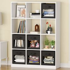 a white bookcase with black bins filled with books