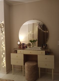 there is a vanity with a mirror and lights on the wall behind it, along with a stool