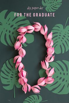 a pink wreath made out of paper on top of a green wall with palm leaves