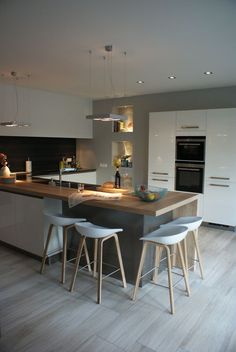 a kitchen with two stools at the center of the island and an oven in the back