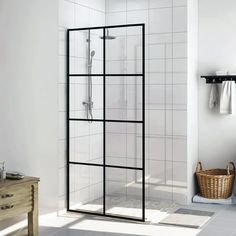 a white tiled bathroom with a walk in shower next to a wooden table and chair