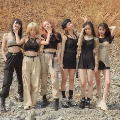 four young women posing for the camera in front of some rocks and dirt with their hands on their hipss