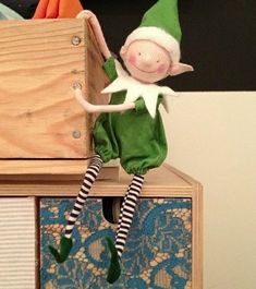 an elf doll sitting on top of a wooden box