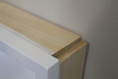 a close up view of the corner of a white door with wood trim on it