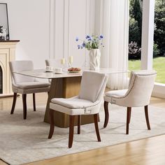 a dining room table with chairs and a vase on top of it in front of a fireplace