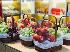 baskets filled with lots of different types of fruit on top of a wooden table in a store