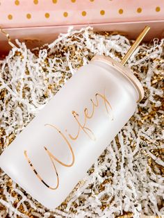 a white glass with gold lettering on it in a pink box filled with confetti