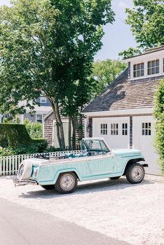 an old blue car parked in front of a house